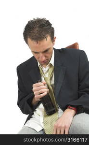 Businessman sitting in a chair with a bottle of beer, obviously drunk