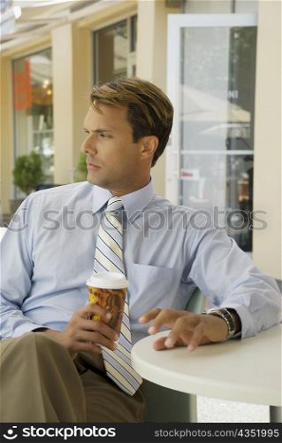 Businessman sitting in a restaurant and holding a disposable cup