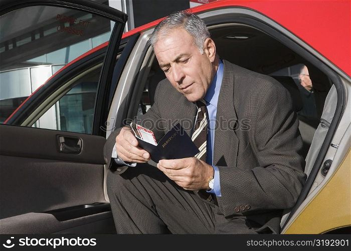 Businessman sitting in a taxi and checking his passport