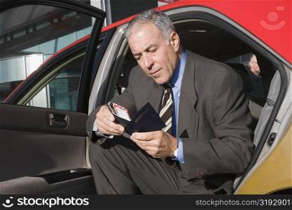 Businessman sitting in a taxi and checking his passport