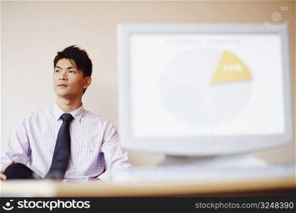 Businessman sitting in an office in front of a model of a computer monitor