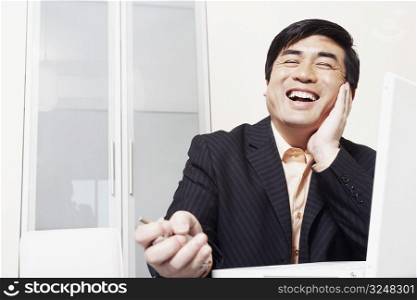 Businessman sitting in front of a laptop laughing