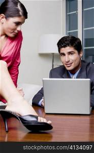 Businessman sitting in front of a laptop with a businesswoman looking at him