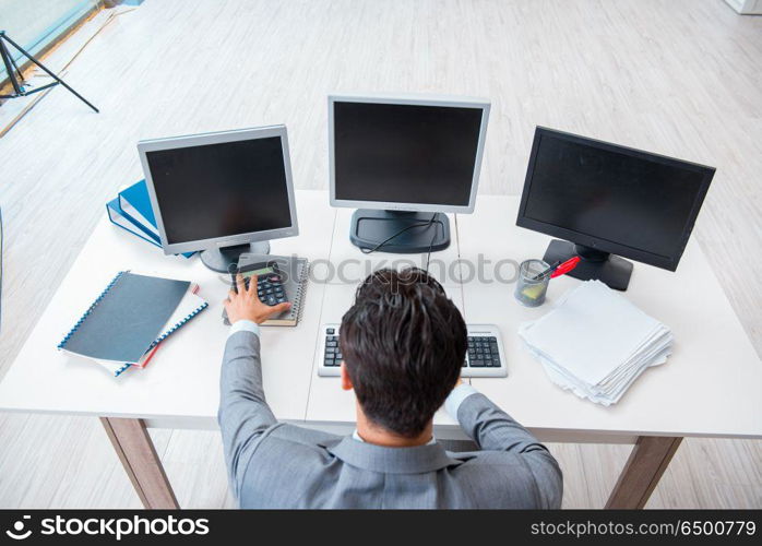 Businessman sitting in front of many screens