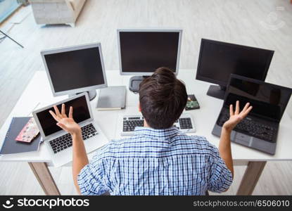 Businessman sitting in front of many screens