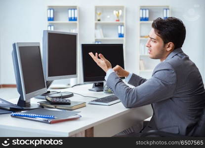 Businessman sitting in front of many screens