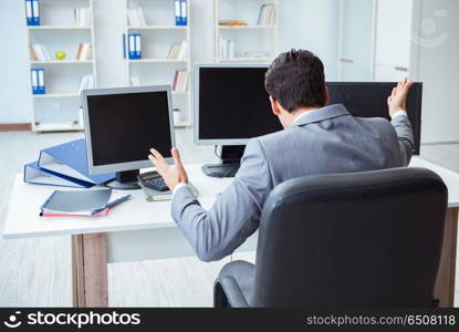 Businessman sitting in front of many screens