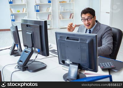 Businessman sitting in front of many screens