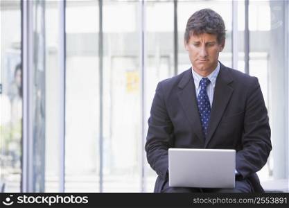 Businessman sitting in office lobby using laptop