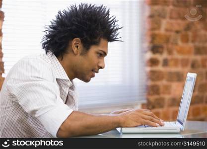 Businessman sitting in office typing on laptop