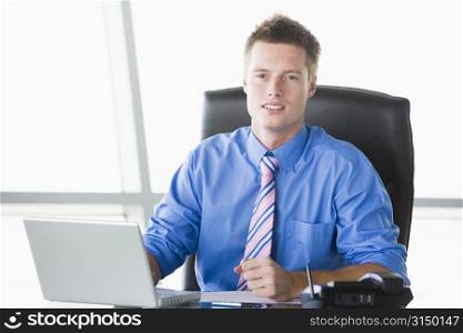 Businessman sitting in office with laptop