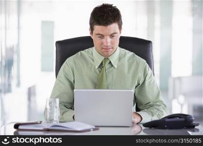 Businessman sitting in office with personal organizer and laptop