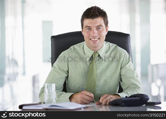 Businessman sitting in office with personal organizer smiling