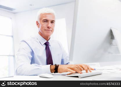 Businessman sitting in office working with computer. Another office day in front of computer