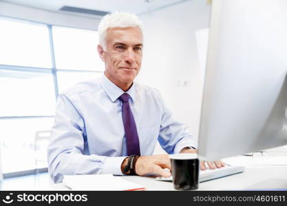 Businessman sitting in office working with computer. Another office day in front of computer