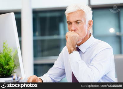 Businessman sitting in office working with computer. Another office day in front of computer