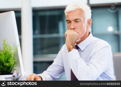 Businessman sitting in office working with computer. Another office day in front of computer