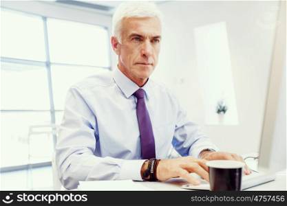 Businessman sitting in office working with computer. Another office day in front of computer