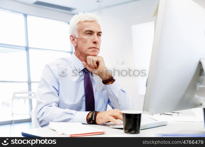 Businessman sitting in office working with computer. Another office day in front of computer