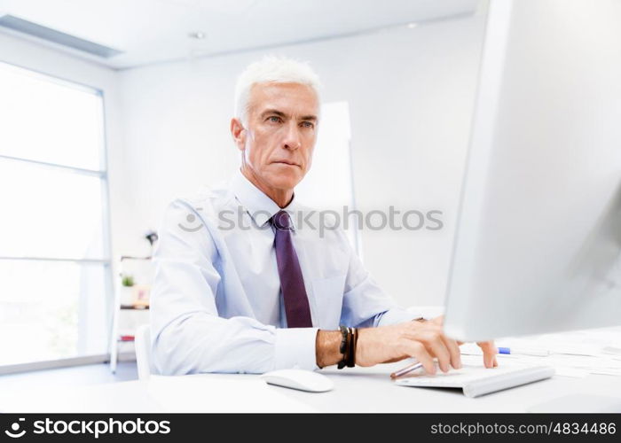 Businessman sitting in office working with computer. Another office day in front of computer