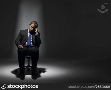 Businessman Sitting In Spotlight