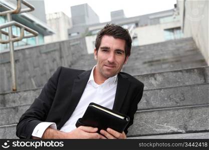 Businessman sitting in stairs out in town