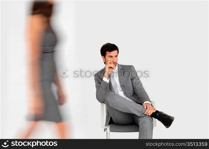 Businessman sitting in waiting room and woman walking by
