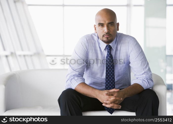 Businessman sitting indoors (high key/selective focus)