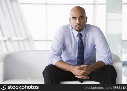 Businessman sitting indoors (high key/selective focus)