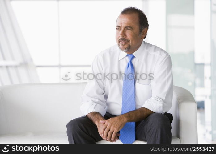 Businessman sitting indoors (high key/selective focus)