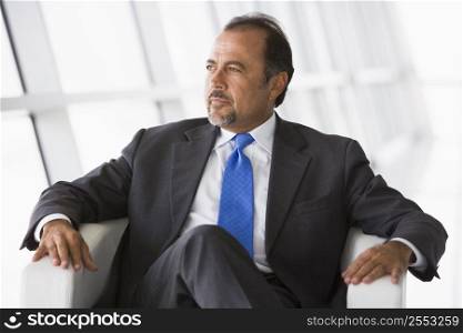Businessman sitting indoors looking out window (high key/selective focus)