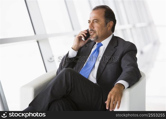 Businessman sitting indoors on cellular phone (high key/selective focus)