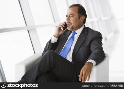 Businessman sitting indoors on cellular phone (high key/selective focus)