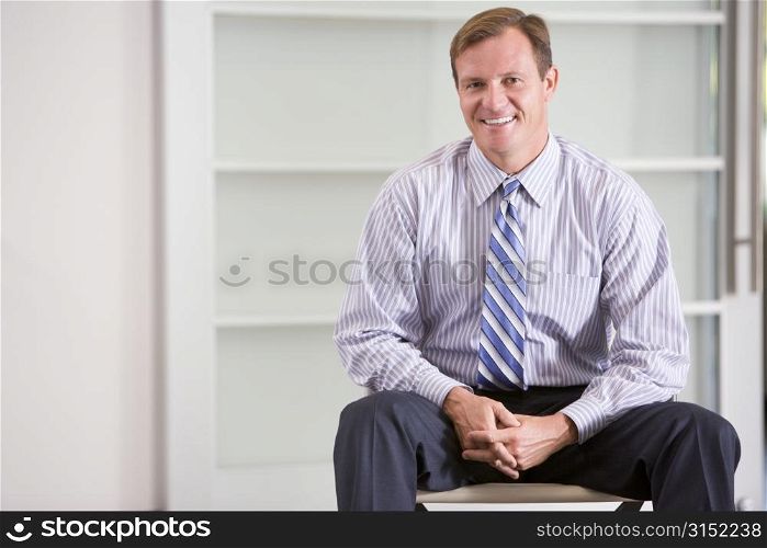 Businessman sitting indoors smiling