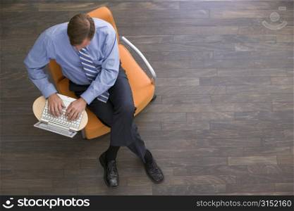 Businessman sitting indoors with laptop