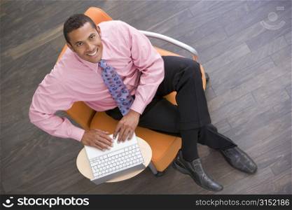 Businessman sitting indoors with laptop smiling