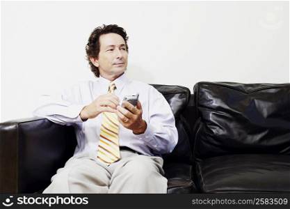 Businessman sitting on a couch and holding a mobile phone