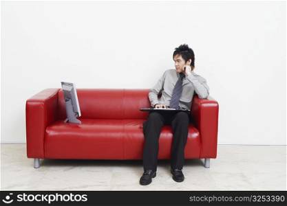 Businessman sitting on a couch and looking at computer monitor