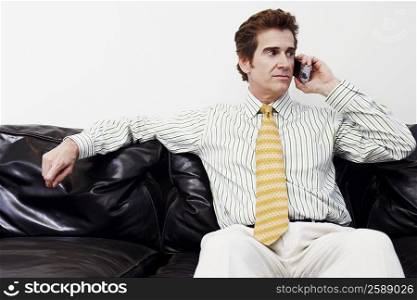 Businessman sitting on a couch and talking on a mobile phone