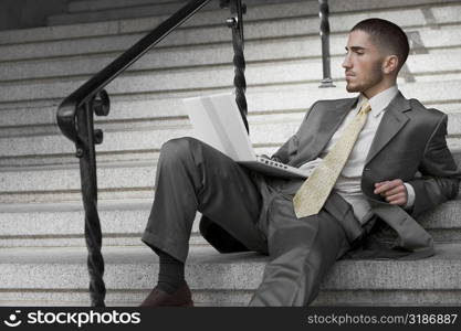 Businessman sitting on a staircase and using a laptop