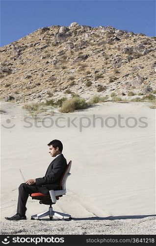Businessman Sitting on Chair in the Desert