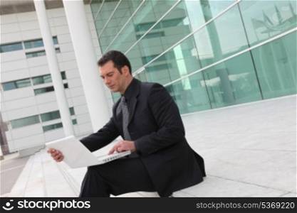 Businessman sitting on stairs with computer