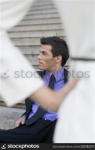 Businessman sitting on steps and looking away