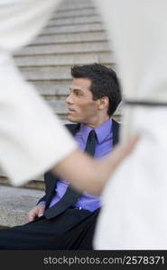 Businessman sitting on steps and looking away