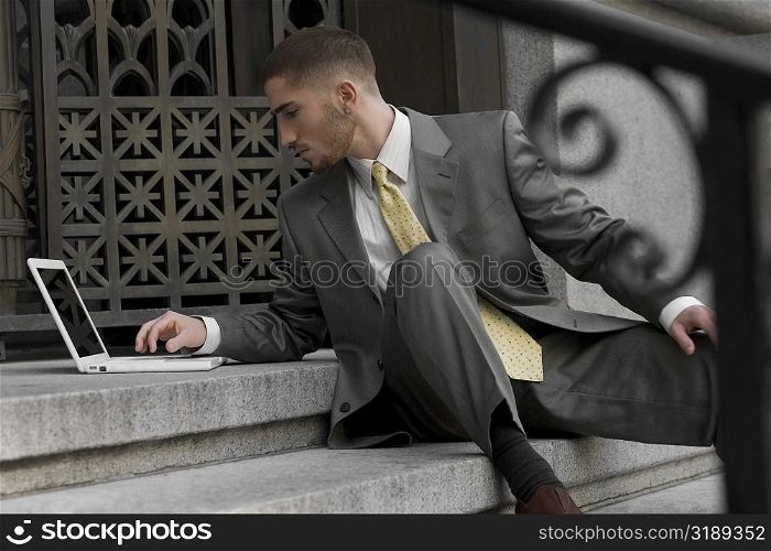 Businessman sitting on steps and using a laptop
