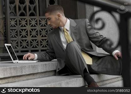 Businessman sitting on steps and using a laptop
