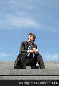 Businessman sitting on steps outdoors low angle view