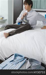 Businessman sitting on the bed and untying necktie