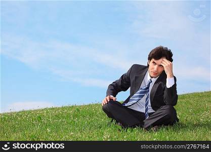 businessman sitting on the meadow and thinking