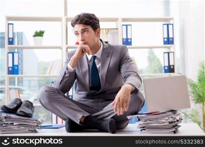 Businessman sitting on top of desk in office